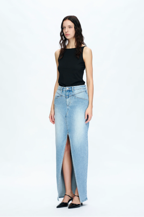 Woman wearing a black sleeveless top and light blue denim skirt on a white background
