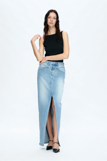 Woman wearing a black top and light blue denim skirt with a slit on a white background