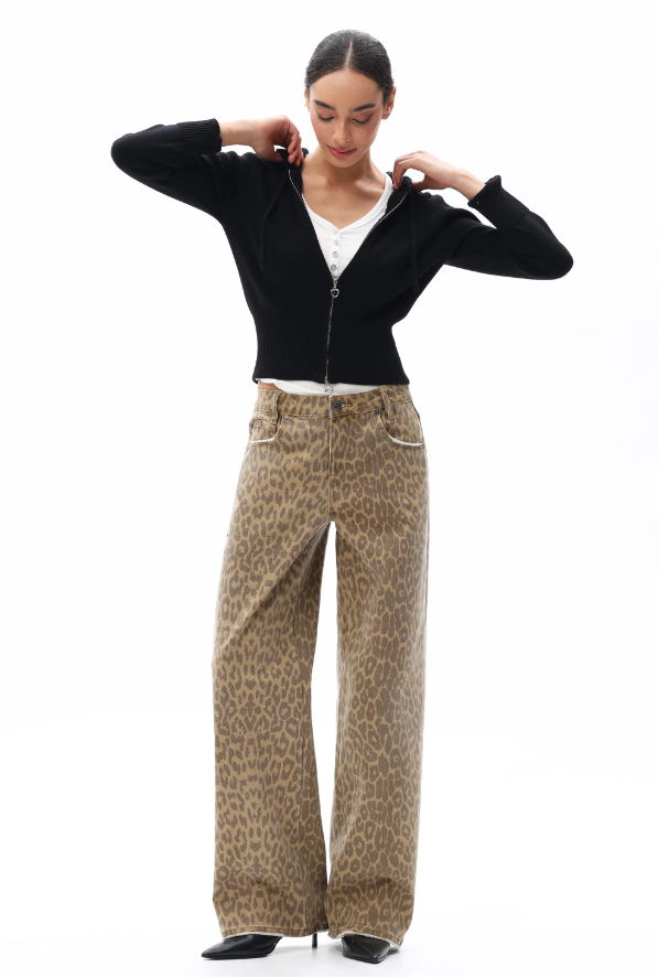 Woman wearing a black top and beige patterned pants on a white background