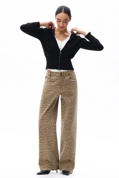 Woman wearing a black top and beige patterned pants on a white background