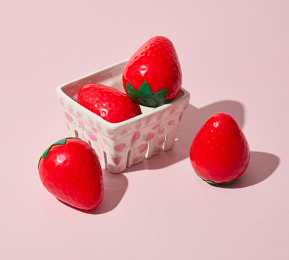 Strawberry-shaped items in a container on a pink background
